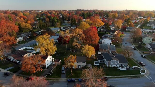 Establishing shot of small town in USA. Colorful autumn fall foliage in neighborhood. Aerial drone dolly shot of homes and houses in United States of America.