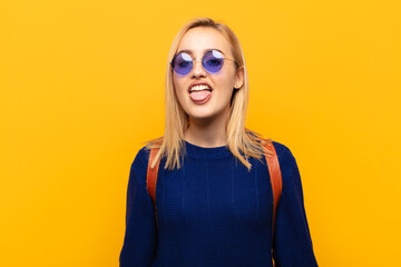 young blonde woman with cheerful, carefree, rebellious attitude, joking and sticking tongue out,...