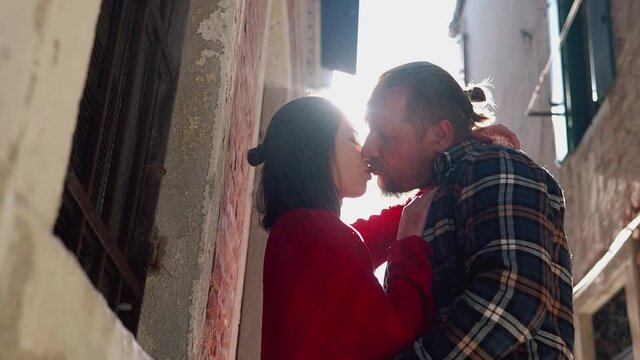 Close shot of young couple kissing and smiling on a bright sunlight. Charming lovers spending their vacation in the most romantic city of Italy. Let the whole world wait. Concept of love and sincerity