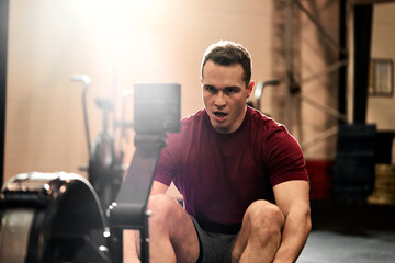 Young man using a rowing machine during a gym workout