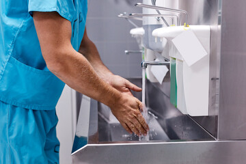 Obraz premium sterility, cleanliness concept. cropped male doctor washing hands after operation, keep hands clean.
