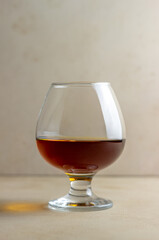 Cognac in a glass on a beige background. Alcoholic beverages. Bar.
