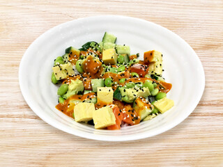 Fresh vegetables salad with salmon, sweet egg, cucamber, avocado diced, white sesame, black sesame and green beans isolate on wooden table background.