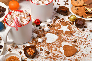 sweet food top view background for merry christmas or new year holiday decoration - chocolate candies, tangerines, cookies, marshmallow and cocoa latte on white wood