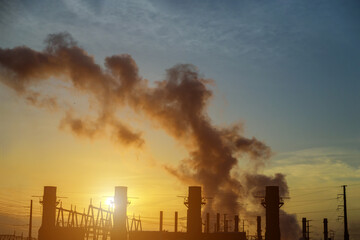 Obraz premium At dusk, the thermal power plants with factory pipe polluting air during sunrise