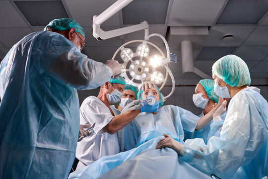 caucasian doctors help the patient to calm down, she woke up during anesthesia. friendly team of surgeons gathered to help people