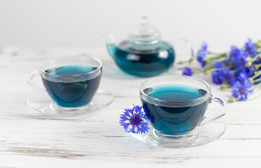 Obraz na płótnie Canvas glass cups and teapot of Butterfly pea tea. Anchan on a white marble background. with bouquet of blue flowers