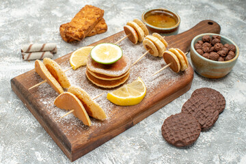 Classic pancakes with fruits on cutting board with cookies biscuits and honey on blue backgrounds