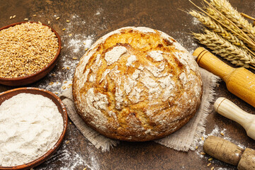 Fresh bread with wheat ears and a bowls of flour and grain