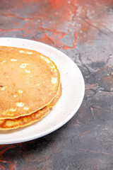 Vertical view of Classic American buttermilk pancakes on a white plate on mixed color background