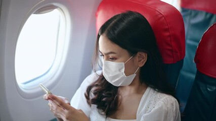 A young woman wearing face mask is using smartphone onboard, New normal travel after covid-19 pandemic concept. - Powered by Adobe