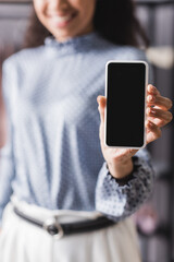 cropped view of african american businesswoman showing smartphone with blank screen on blurred background