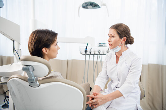 A young female dentist consulting her patient in the clinic.