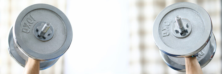 Close-up of strong and fit person lifting heavy dumbbells at home. Sport and active lifestyle. Adult laying on back and training for health and muscle body. Quarantine period concept