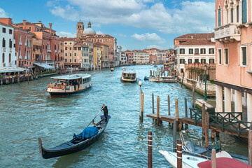 gondola and tourist ships sailing along the Grand Canal in Venice against the backdrop of beautiful houses and blue sky