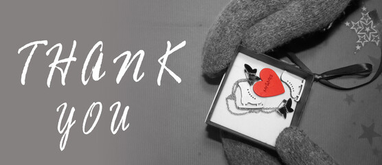 Thank you text on the background of the gift. Gift box in hands