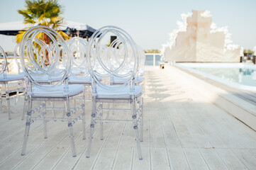 Glass chairs stand in a row in a beautiful wedding outing ceremony