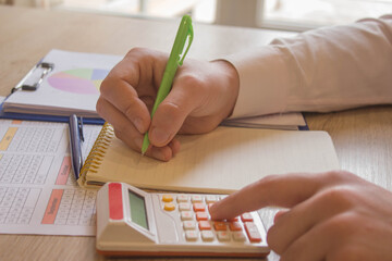Man is taking notes of saving money in a notebook, with a money jar and a business report