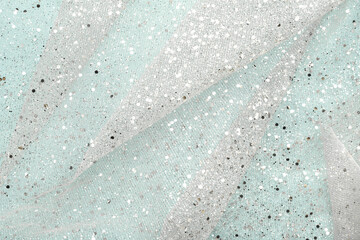 Sparkling fabric decorated silver glitter on light blue background.