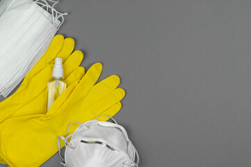 Masks, yellow gloves, respirators and antiseptic on a gray background.