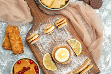 Close up view of simple pancakes with lemons on cutting board and cookies orange towel on blue background