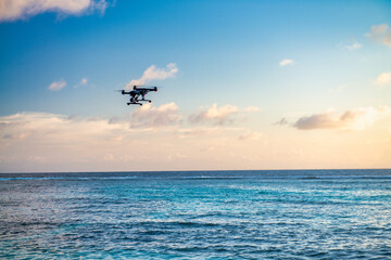 Fototapeta na wymiar Modern drone overflying the ocean at sunset