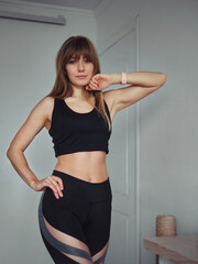 Gorgeous young athletic active sportive blonde woman in top and leggins sport outfit for yoga exercise posing in her home room indoors