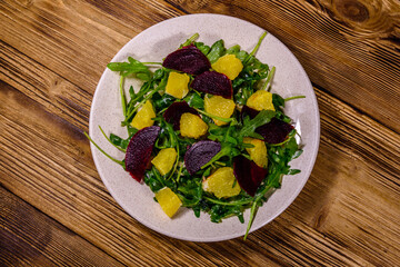 Salad with arugula, orange and beetroot in a ceramic plate. Top view