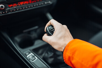 Man's hand switches manual transmission closeup. Manual gearbox handle stick at the car. Man is...