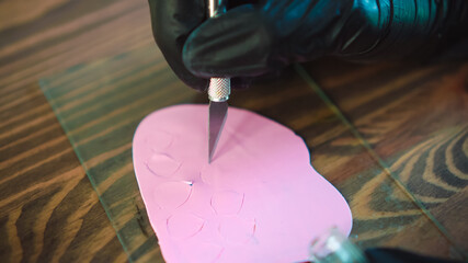 Artisan cuts polymer clay by cutter. Master works by knife in workshop.