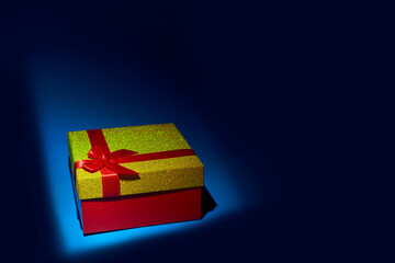 Gold gift box on a blue background, Christmas gift, Valentine's day gift or women's day gift.