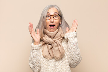 middle age woman looking shocked and astonished, with jaw dropped in surprise when realizing...