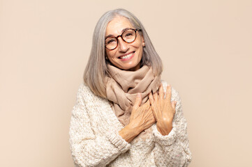 middle age woman feeling romantic, happy and in love, smiling cheerfully and holding hands close to...