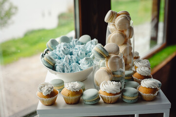 Candy bar. Table with different sweets for party. Sweet table. French macaroni, marshmallows and cupcakes on a white table.