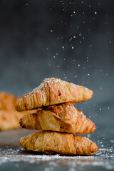 Close up of pile of delicious croissants on a dark background. Homemade croissants. Sugar glass...