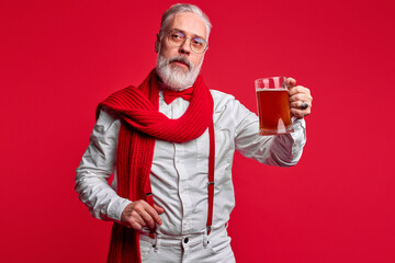 bad santa with glass of beer posing isolated over red background, portrait. happy new year concept