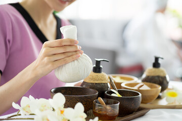 Asian attractive masseuse working in skin care spa with ingredient and flower