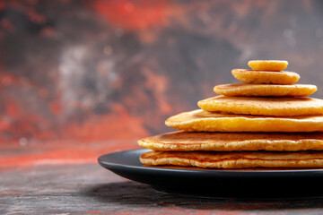 Side view of delicious classic American pancakes on mixed color background