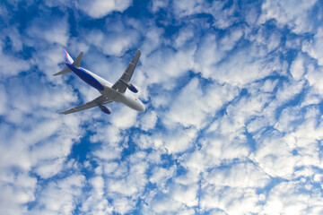 Commercial passenger airplane jet flying in dramatic clouds in sky altitude. Travel concept and tourism