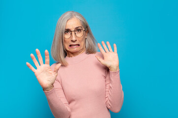 middle age woman feeling terrified, backing off and screaming in horror and panic, reacting to a...