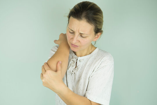 Beautiful woman holding her elbow with pain and arm ache, isolated.