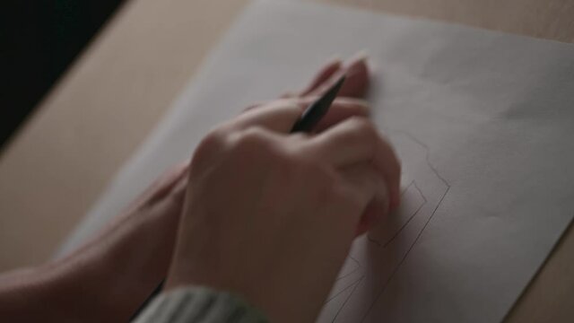 The designer tweaks the sketch with an eraser on a piece of paper. Close-up of a hand with a pencil and an eraser.