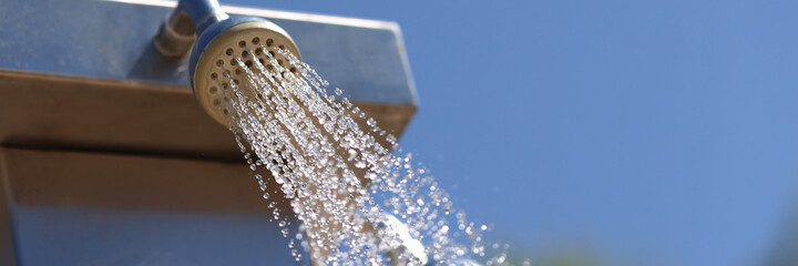 Water is pouring from cheap summer street tap. Service and services of hotels near pool and on...