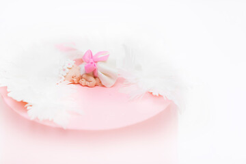 Pink baptism cake with a little baby figurine. Background baptism of a girl.