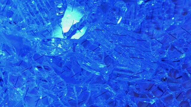 Broken glass in blue light, macro shot as background. Tempered glass pieces.