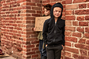 Fototapeta na wymiar two caucasian homeless boys begging in city streets, suffering from poverty and loneliness, want to find shelter and food donation