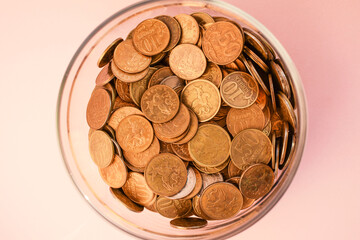 Metal Russian coins lie in a glass jar isolated on a light background. Store and protect savings. Low salary. Financial crisis, currency devaluation concept. Selective focus.