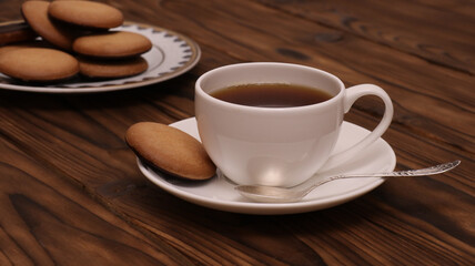 White cup of coffee with cookies on wooden table. Coffee time concept.