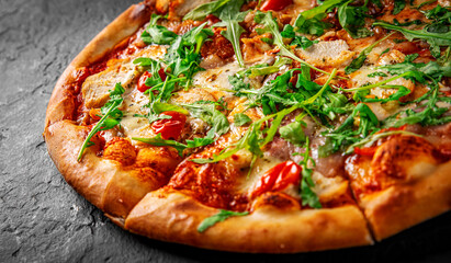 Pizza with chicken, bacon, cheese, tomato and arugula. Italian pizza on Dark grey black slate background