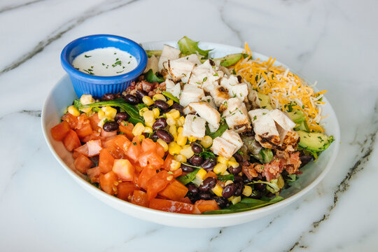 Southwest salad with tomatoes beans corn chiken cheese and avacados with a side of ranch